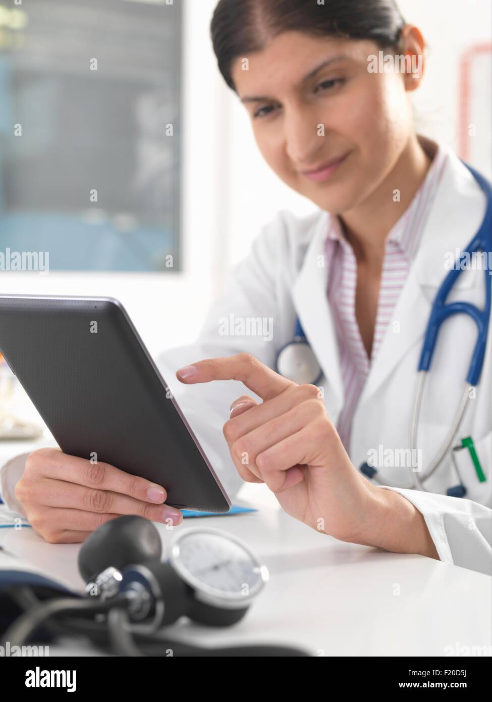 Medico donna aggiornamento record medici utilizzando tavoletta digitale Foto Stock