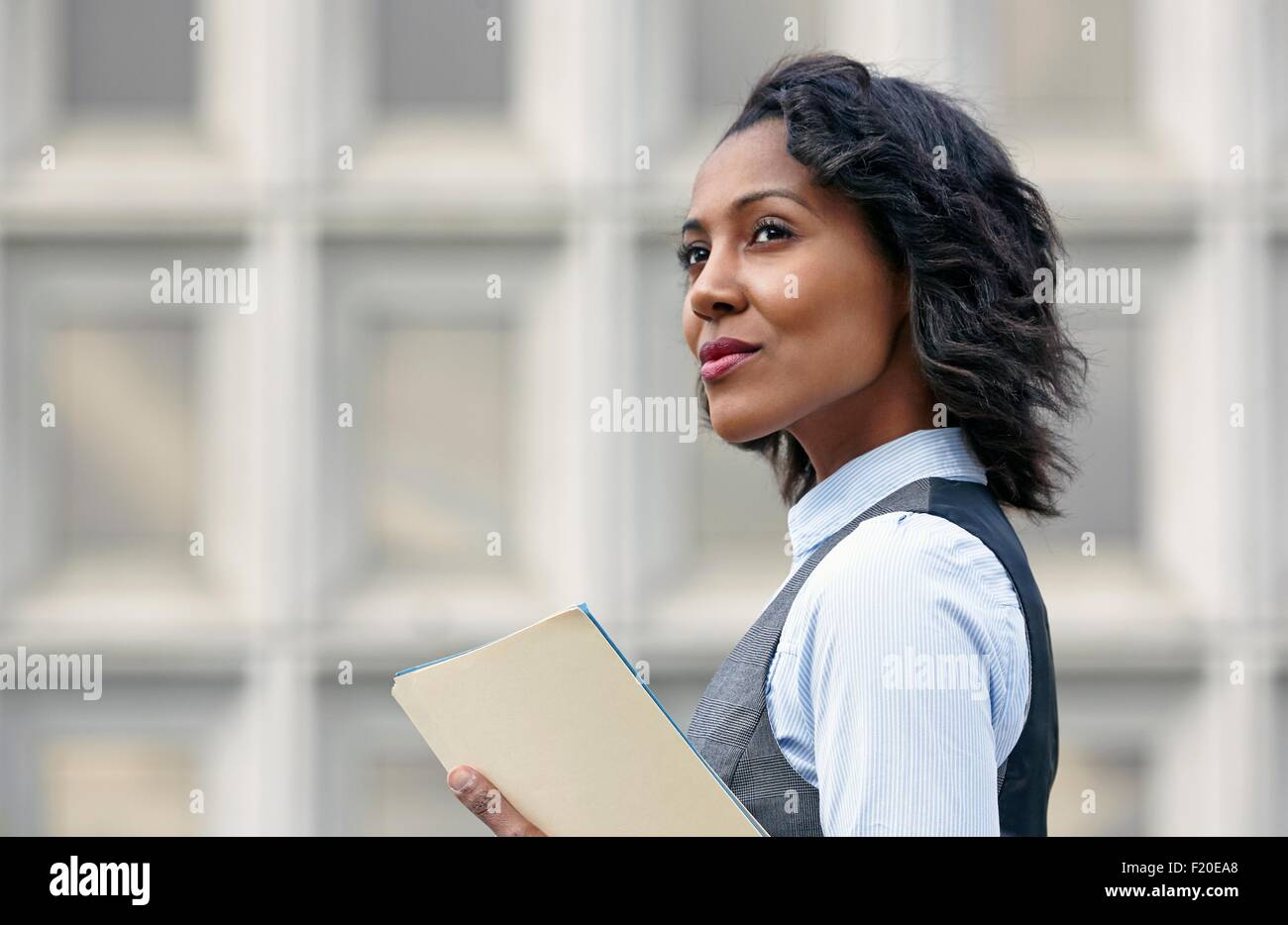 Ritratto di giovane donna d'affari in azienda della carta di lavoro, cercando di distanza, vista laterale Foto Stock