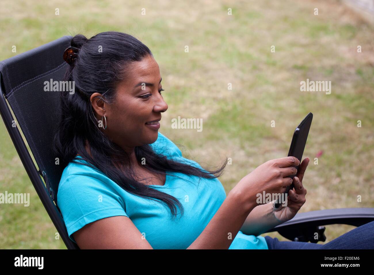 Coppia donna seduta su giardino Sdraio lettura digitale compressa Foto Stock