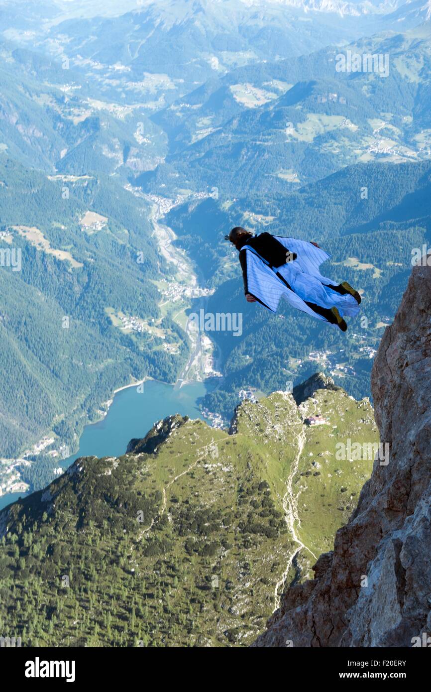 Maschio a ponticello di base wingsuit volando sopra la valle, Dolomiti, Italia Foto Stock