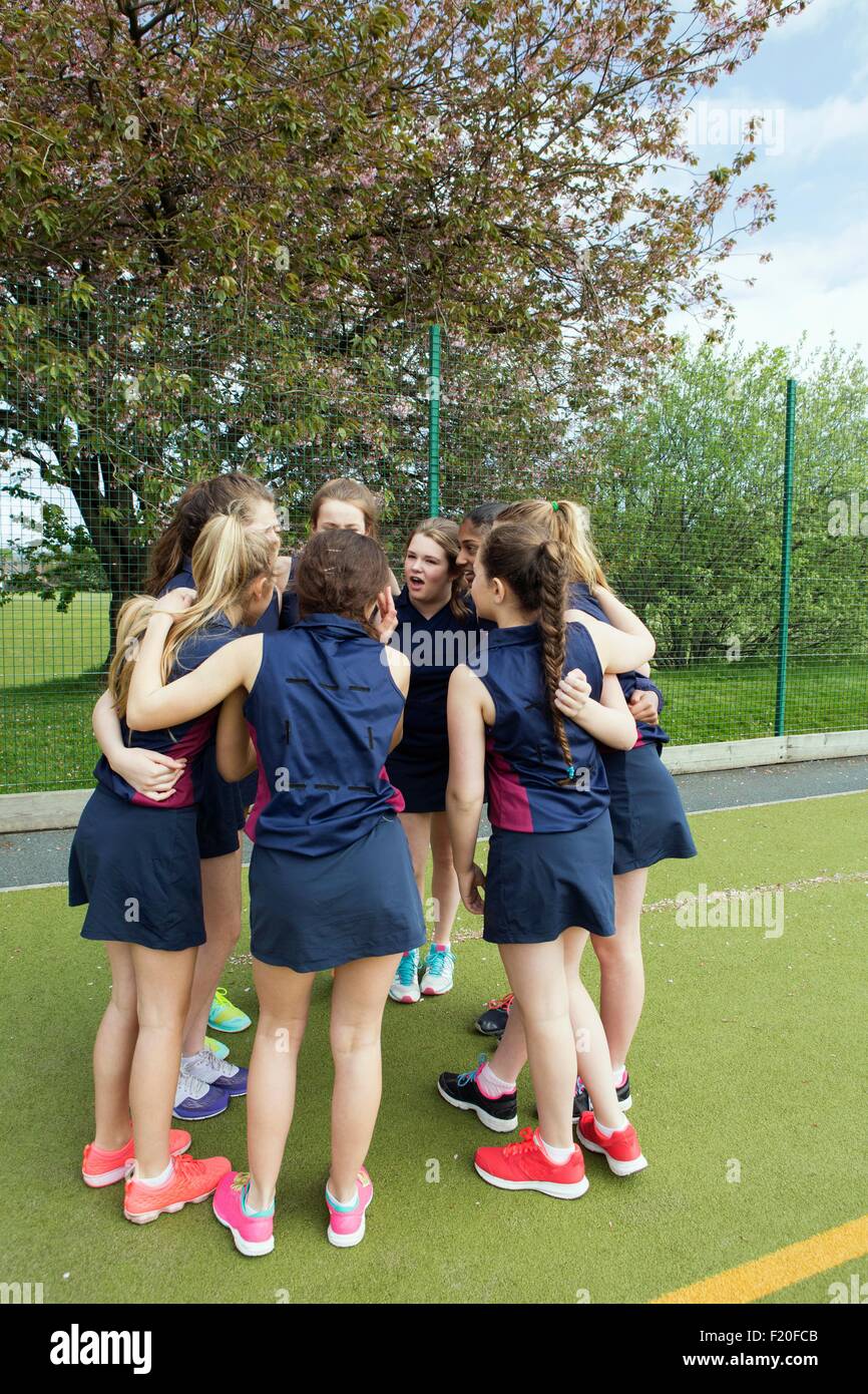 Un gruppo di ragazze in huddle sul campo sportivo Foto Stock