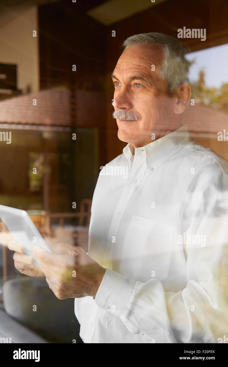 Senior uomo a casa, utilizzando tavoletta digitale Foto Stock