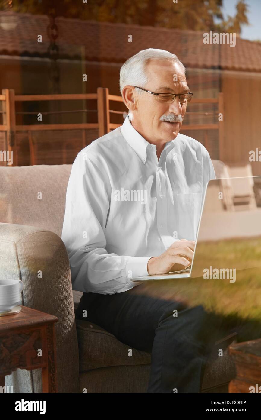Senior uomo a casa, utilizzando laptop Foto Stock