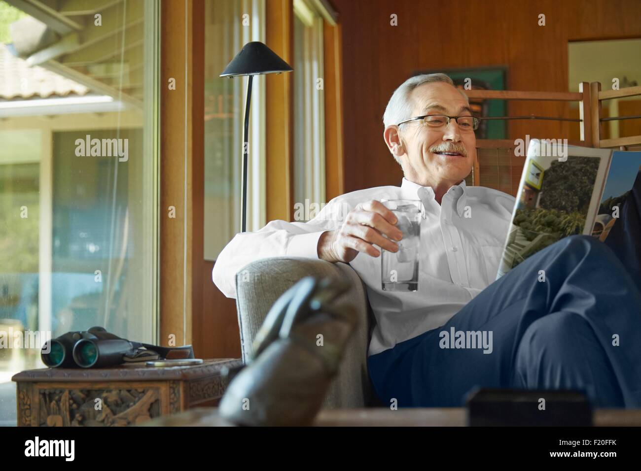 Senior uomo a casa, rivista di lettura Foto Stock