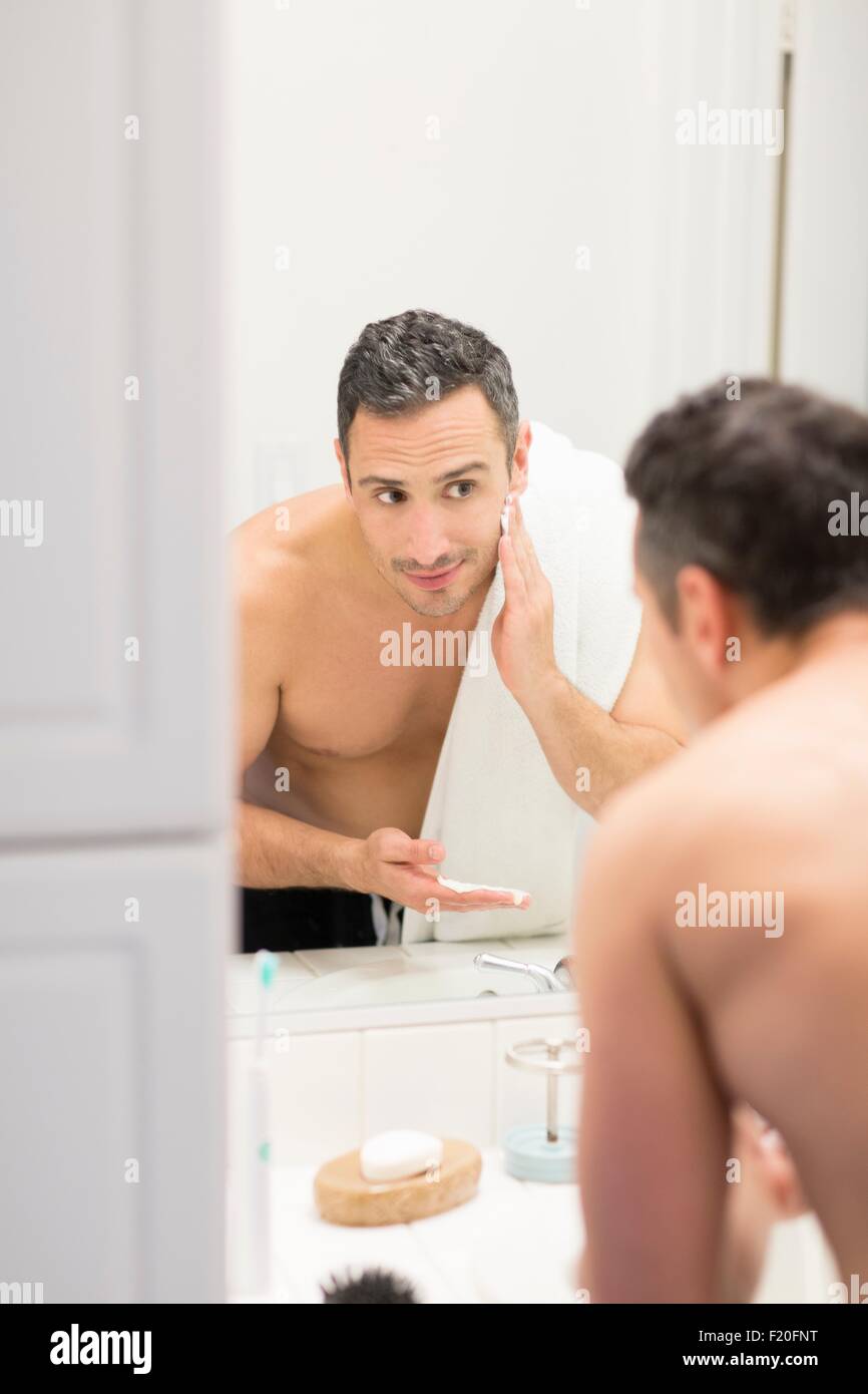 Metà uomo adulto, guardando in uno specchio, applicazione di schiuma da  barba a faccia vista posteriore Foto stock - Alamy