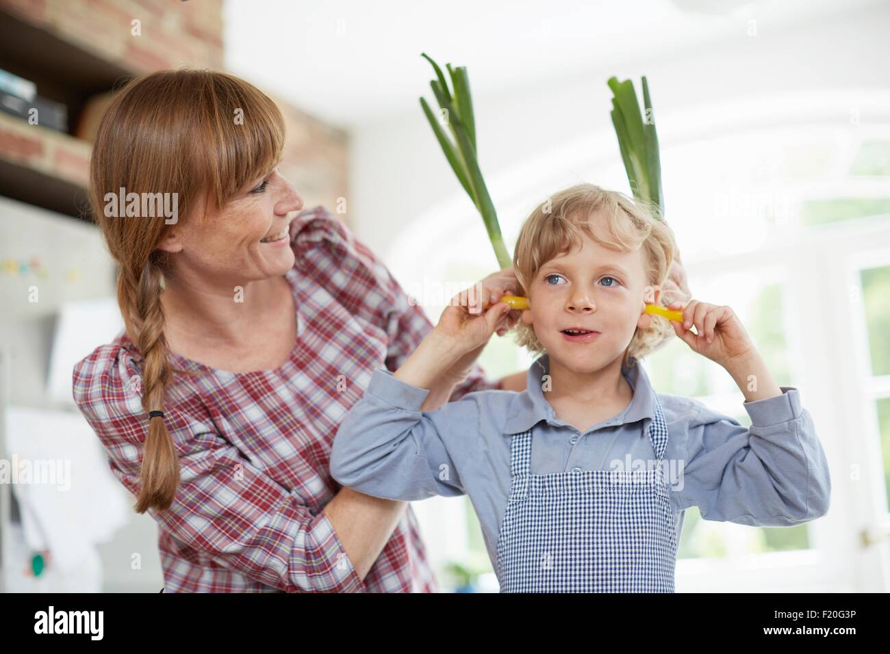 Madre e figlio giocando con il vegetale in cucina Foto Stock