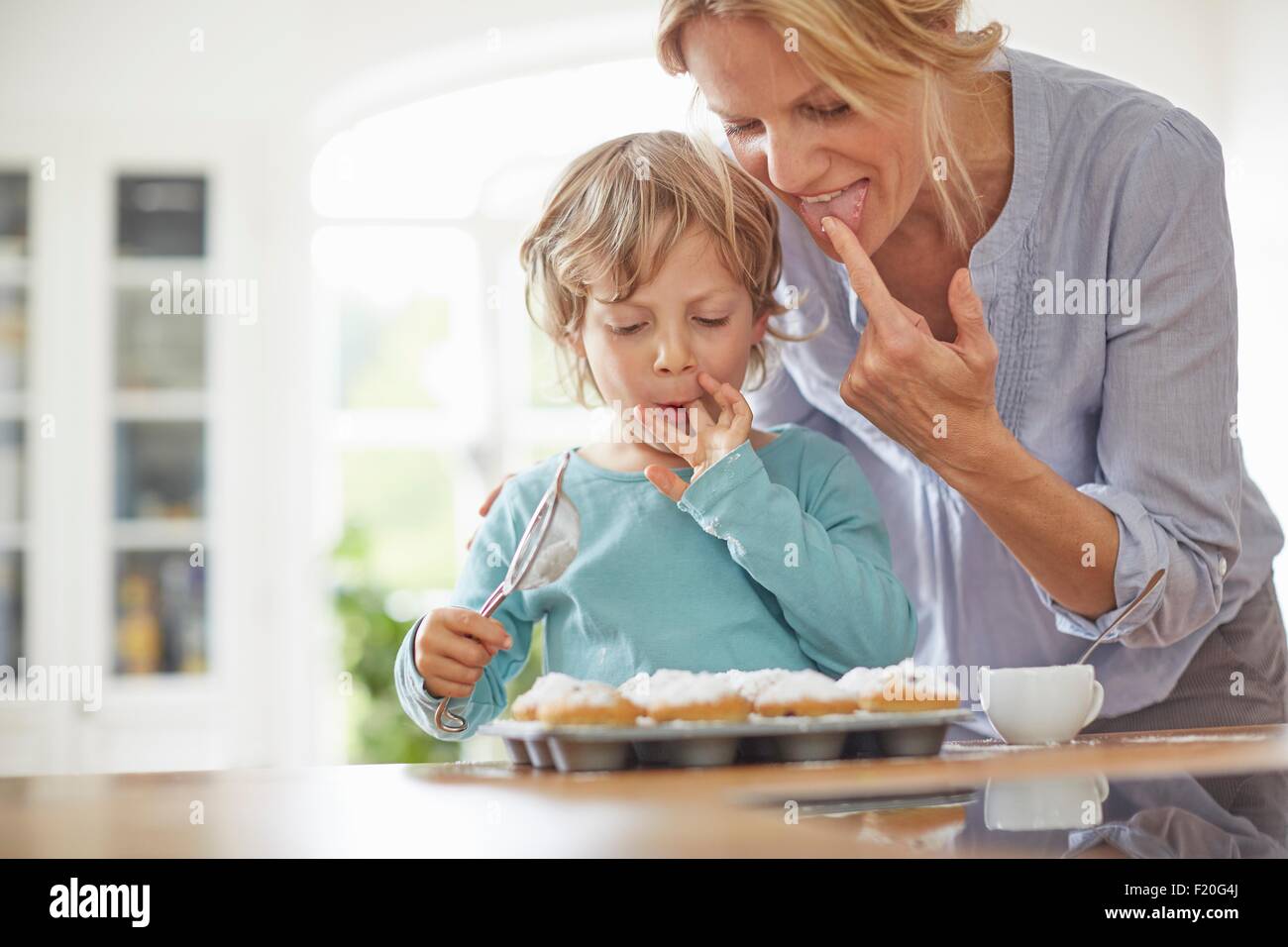 Madre e figlio rendendo i tortini in cucina Foto Stock