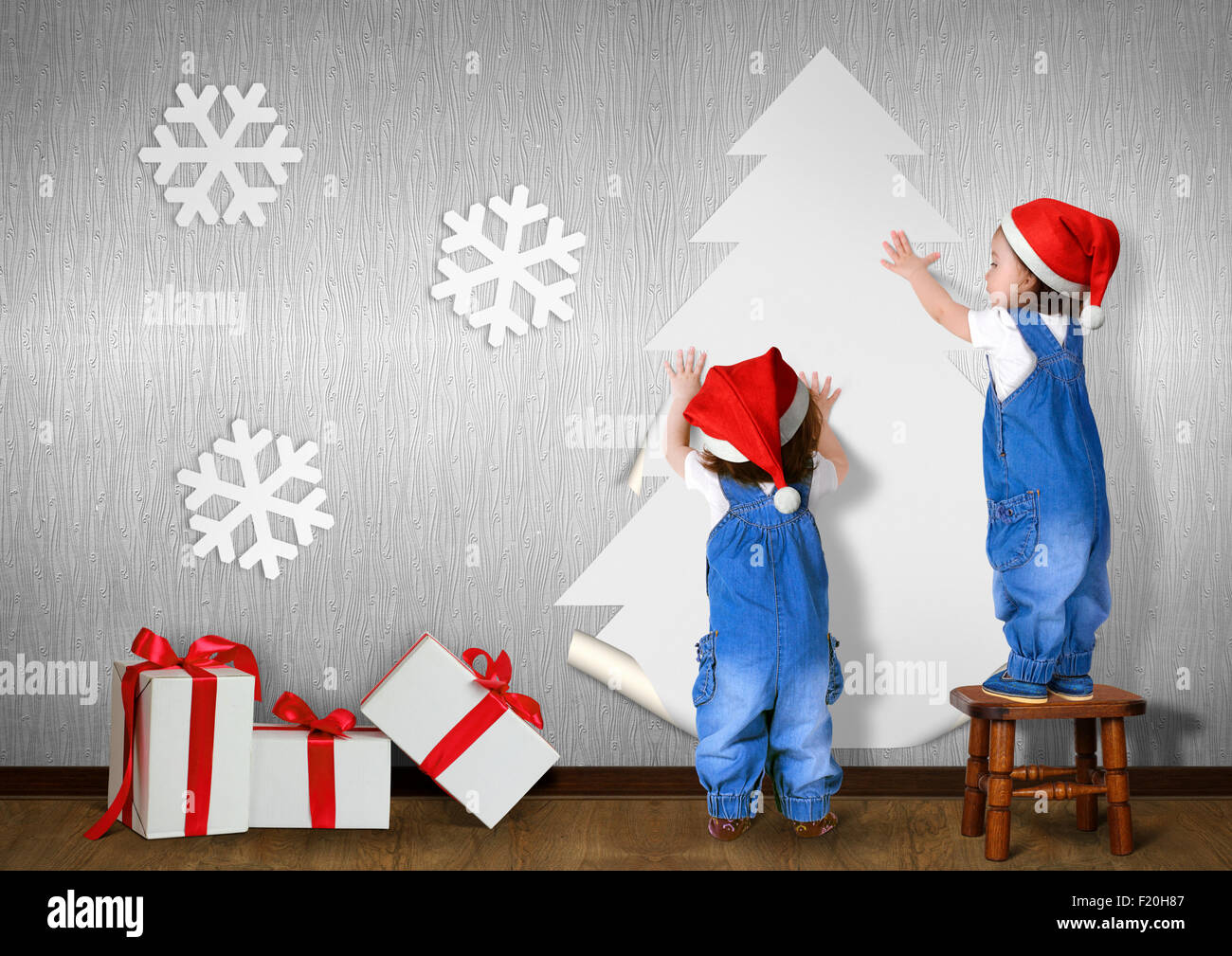 Poco gemelli vestito Santa hat, colla albero di Natale sulla parete di casa, concetto di natale Foto Stock