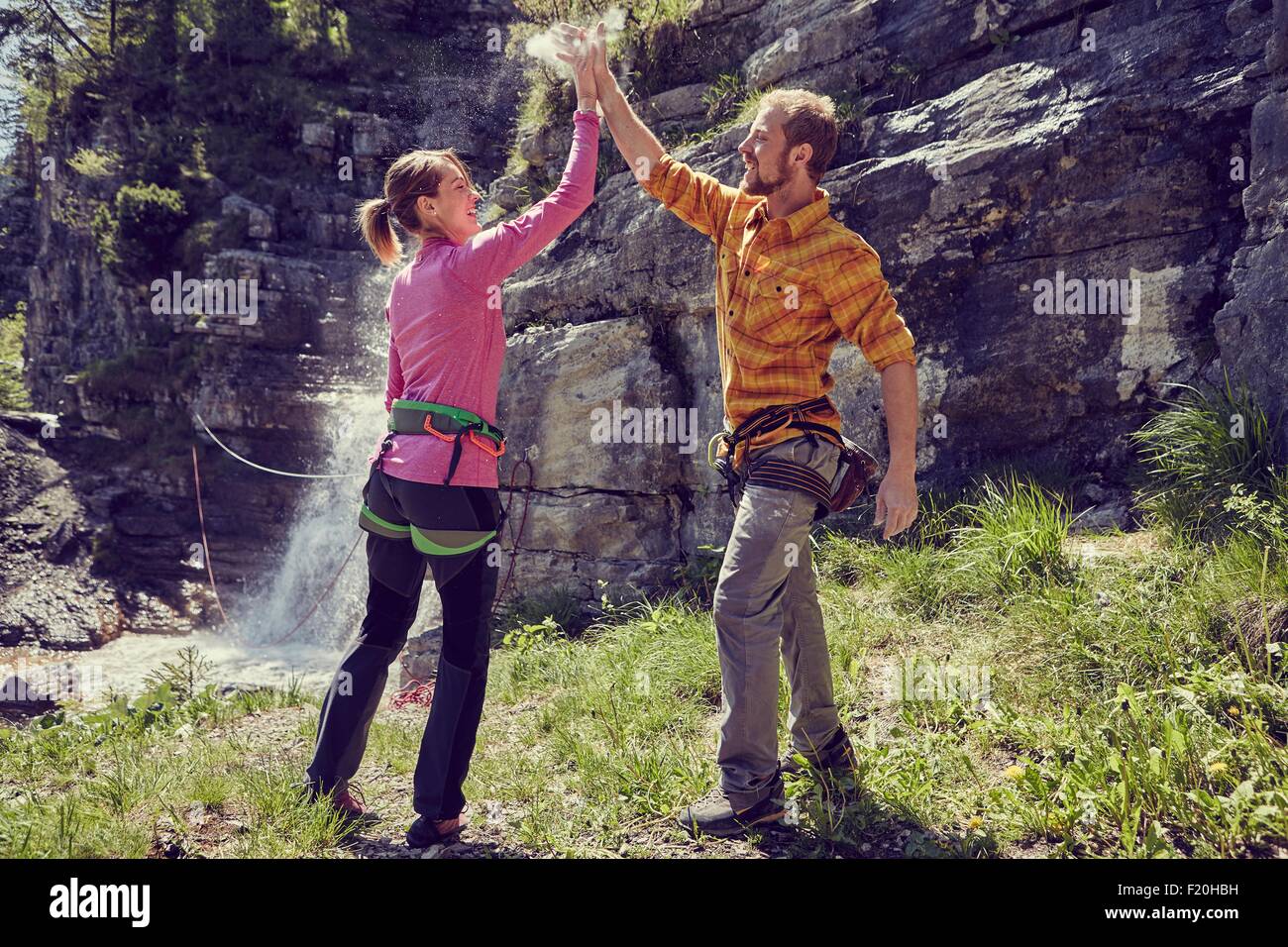 Gli alpinisti dando alta cinque, cascata in background, Ehrwald, Tirolo, Austria Foto Stock