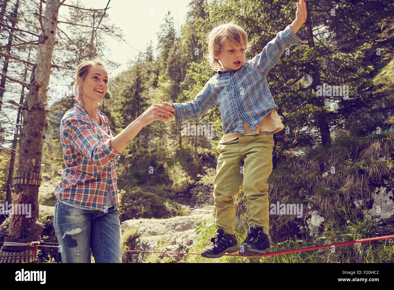 Bilanciamento del ragazzo sulla corda con aiuto dalla madre, Ehrwald, Tirolo, Austria Foto Stock