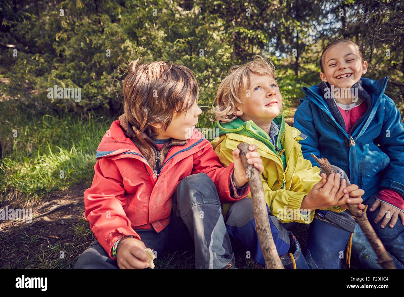 Tre bambini seduti insieme nella foresta Foto Stock