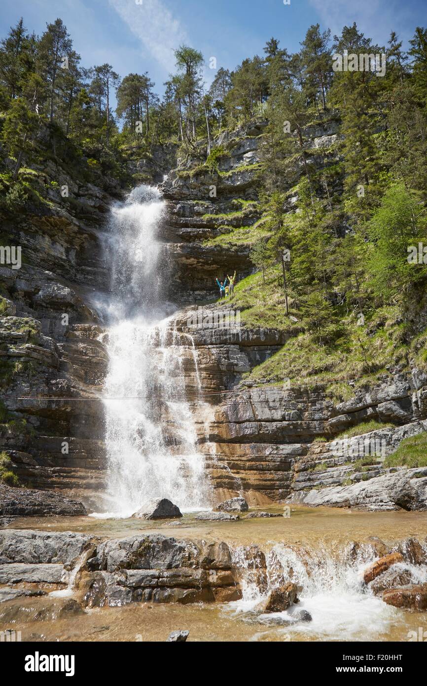 Famiglia giovane in piedi in alto accanto a cascata che scorre, Ehrwald, Tirolo, Austria Foto Stock