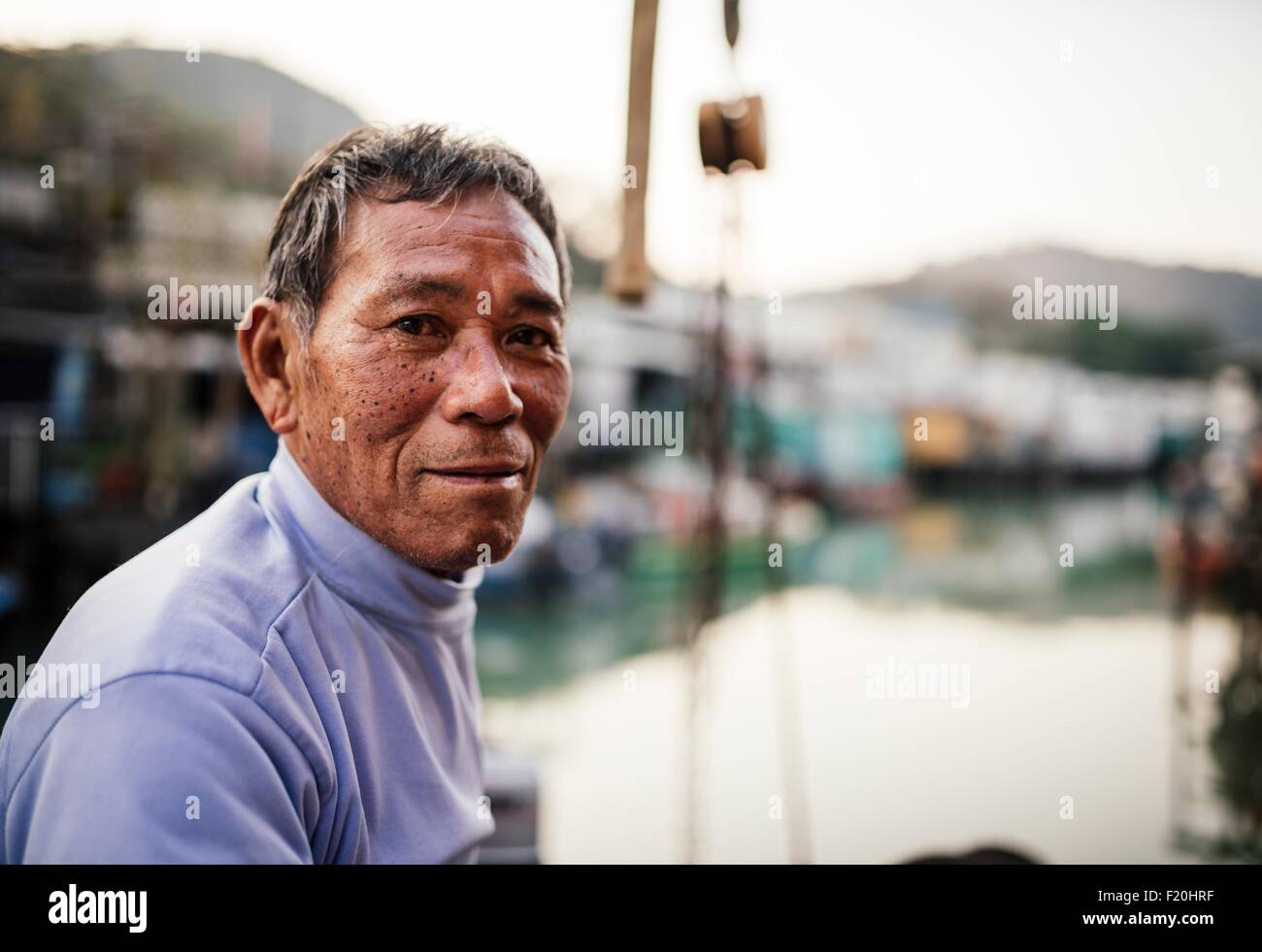Ritratto di uomo anziano, vista laterale e di fronte di barche sull'acqua, guardando la fotocamera Foto Stock