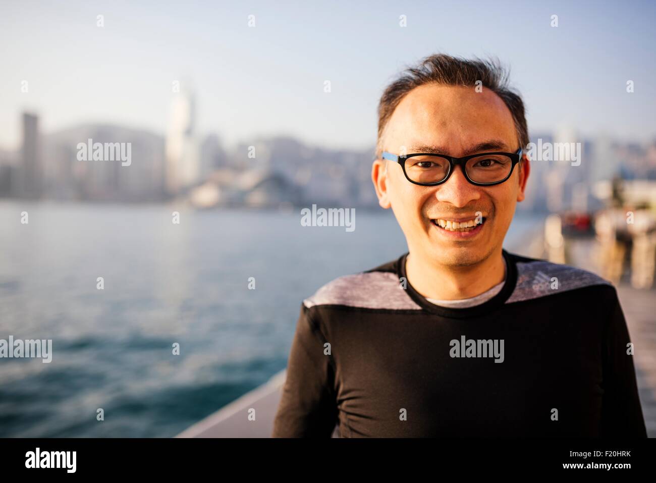 Ritratto di metà uomo adulto con gli occhiali di fronte acqua, guardando alla fotocamera a sorridere Foto Stock