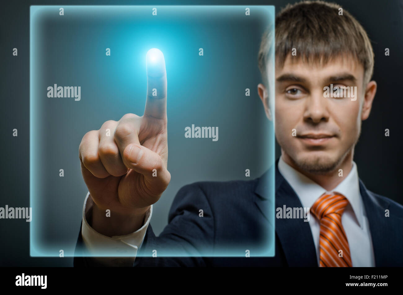 Imprenditore bello dito punto toccare il sensore pannello, su sfondo blu scuro Foto Stock