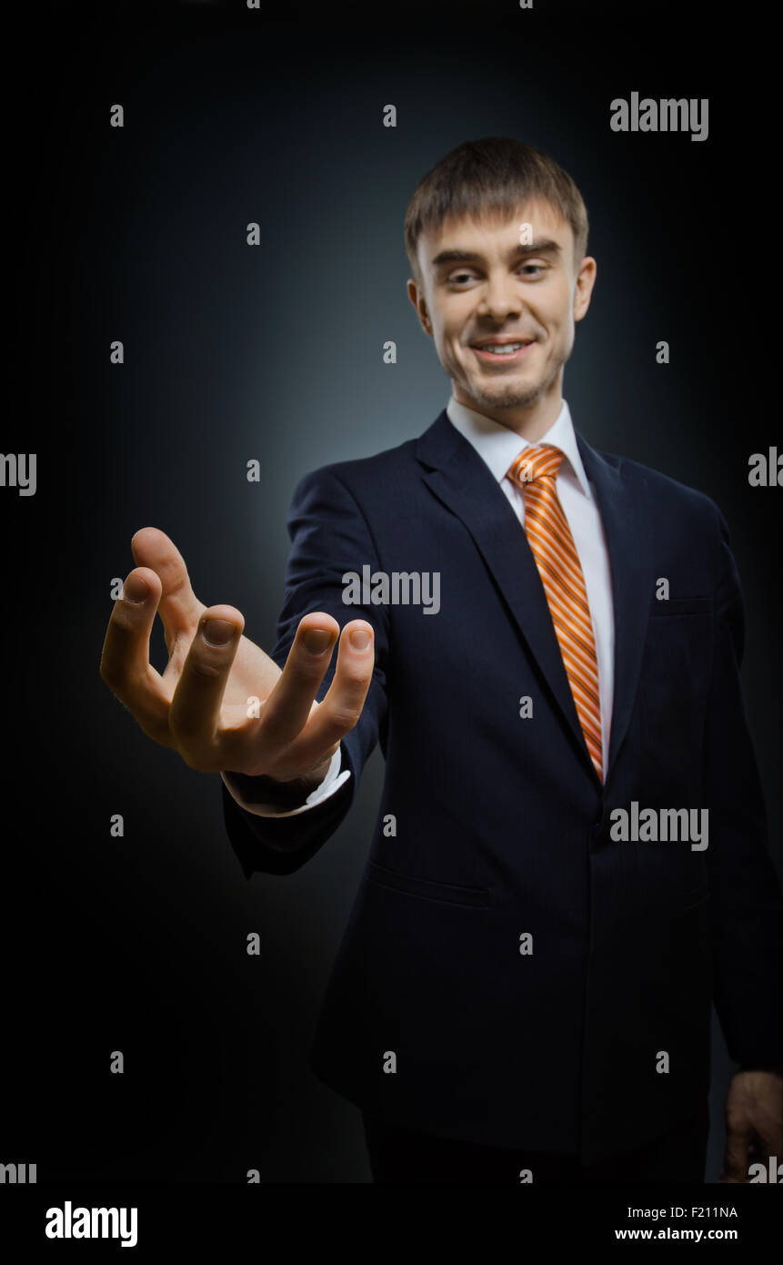 Imprenditore tenere raggiungere fuori mano , su sfondo blu scuro, concetto di business Foto Stock