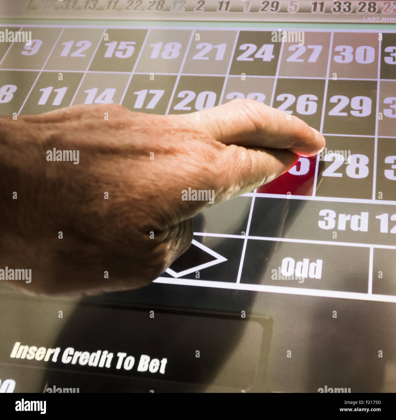 Uomo con le dita incrociate giocando su fixed odds roulette macchina in Bookmakers. Regno Unito Foto Stock