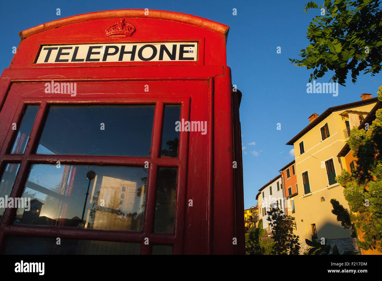 L'Italia, Toscana, Lucca, Barga, British telefono box con facciate delle vecchie case di città in background. Foto Stock