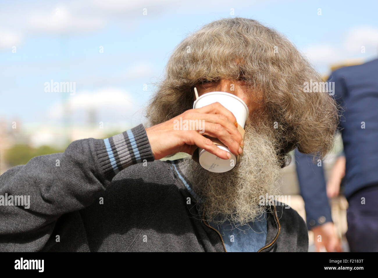 Un eccentrico street persona godendo un take away tazza di tè all'aperto in un pomeriggio soleggiato sulla southbank di Londra a Lambeth Foto Stock