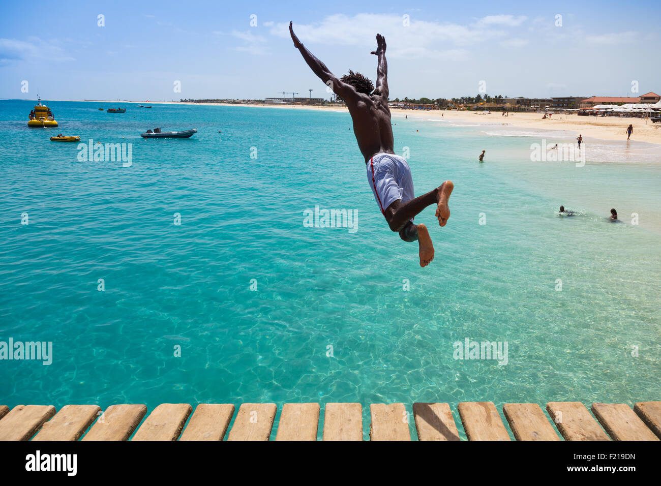 Teenage del Capo Verde ragazzo saltando sulle acque turchesi della spiaggia di Santa Maria in Sal Capo Verde - Cabo Verde Foto Stock