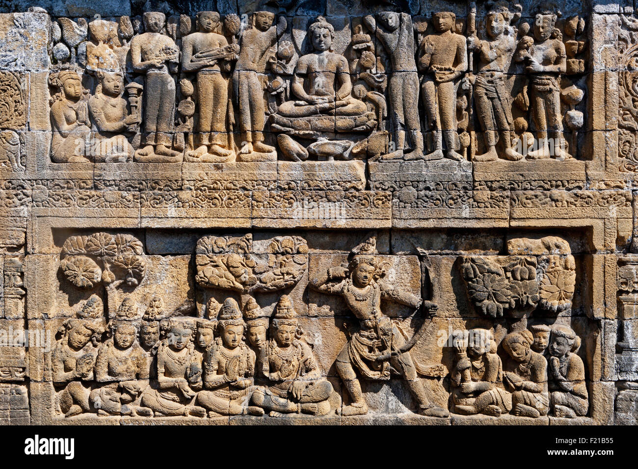 Indonesia Java Borobudur due-tiered bassorilievo che mostra il Buddha seduto e seguaci sul livello più alto e un soldato o re con la prua e la Foto Stock