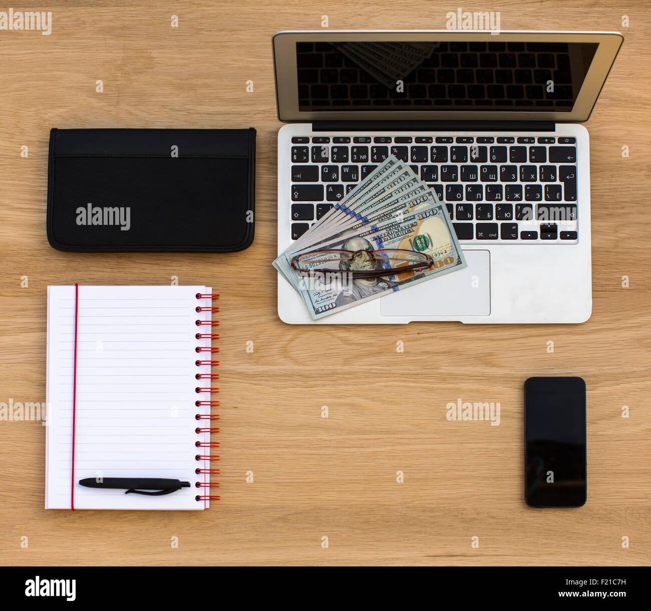 Business card, Laptop e centinaia di fatture del dollaro, Notebook, penna e occhiali, giacente su legno di quercia texture, vista dall'alto. Foto Stock