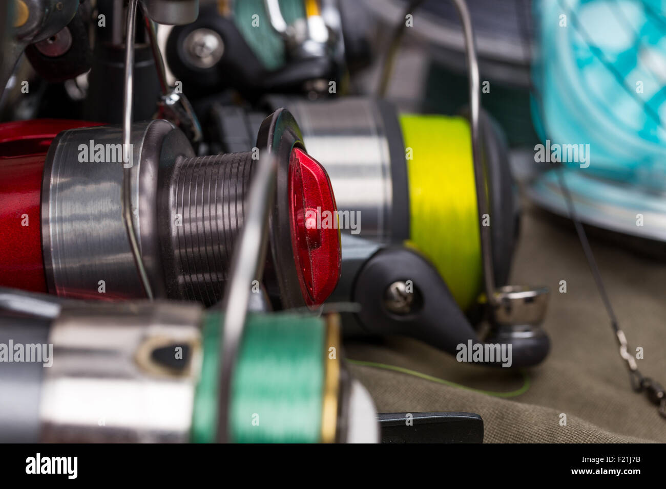 Mulinelli per la pesca con la linea diversi colori su sfondo di stoffa Foto Stock