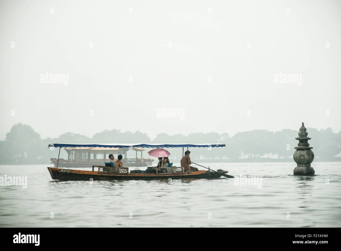 I turisti facendo una gita in barca sul Lago Ovest avvicinarsi a uno dei tre pagode di pietra che salgono dal acqua , Hangzhou, Cina e Asia Foto Stock