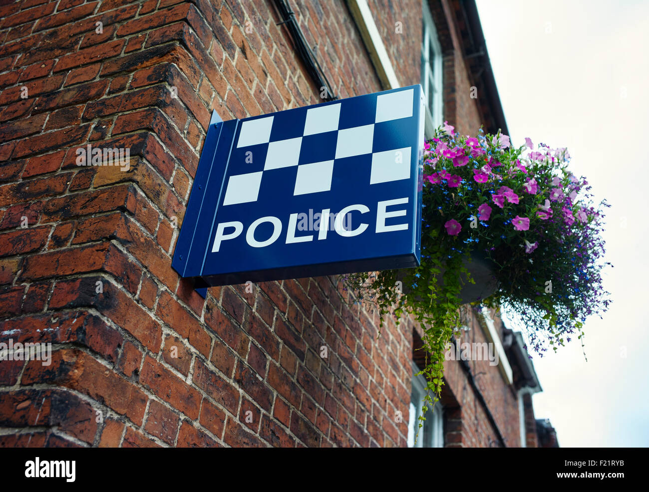 Cartello della polizia sul muro con cesto di fiori a Stone, Staffordshire Foto Stock