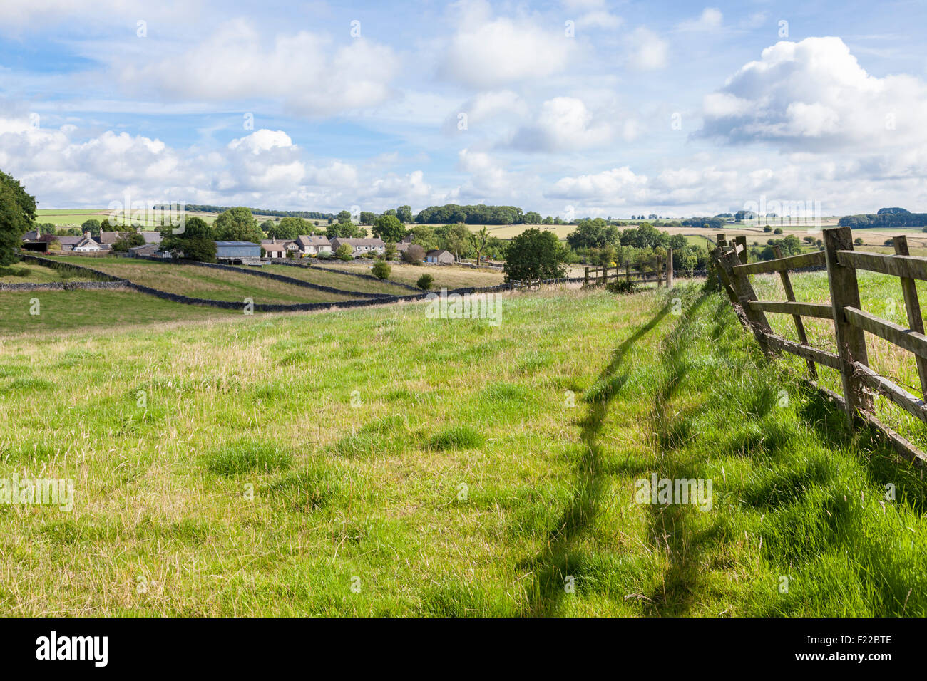 Derbyshire campagna con il villaggio di Monyash nella distanza. Derbyshire, Parco Nazionale di Peak District, England, Regno Unito Foto Stock