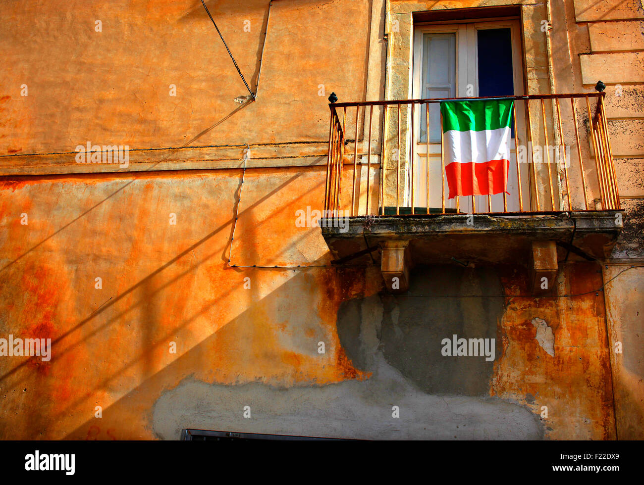Il vecchio edificio in Fontecchio, Italia, mostrando bandiera italiana, balcone e stucco arancione. Foto Stock