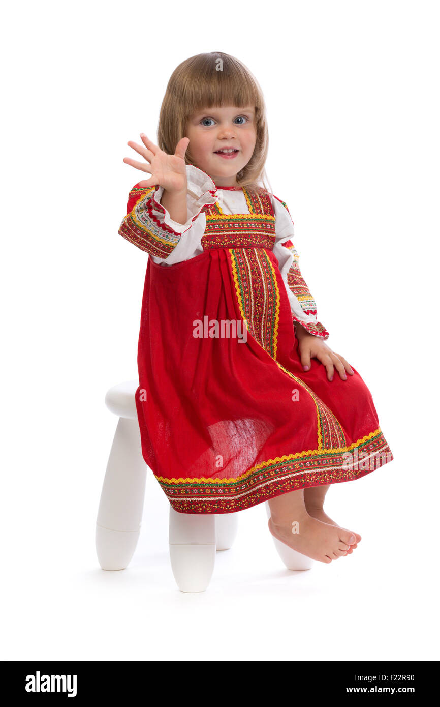Bambina in rosso vestito tradizionale su una sedia. Isolare il bianco. Foto Stock