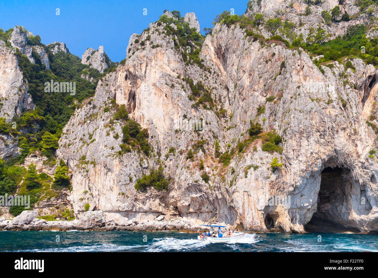 Rocce costiere di isola di Capri, piccolo piacere motoscafo con i turisti vanno vicino alla costa Foto Stock