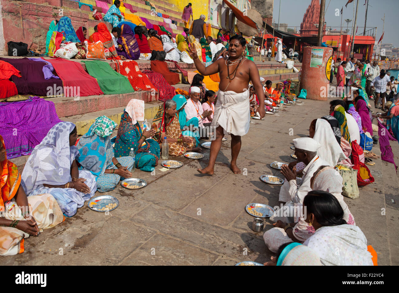 Un Pandit (uomo santo e il sacerdote che compie cerimonie) conduce puja (preghiera) con i pellegrini sul ghats a Varanasi Foto Stock