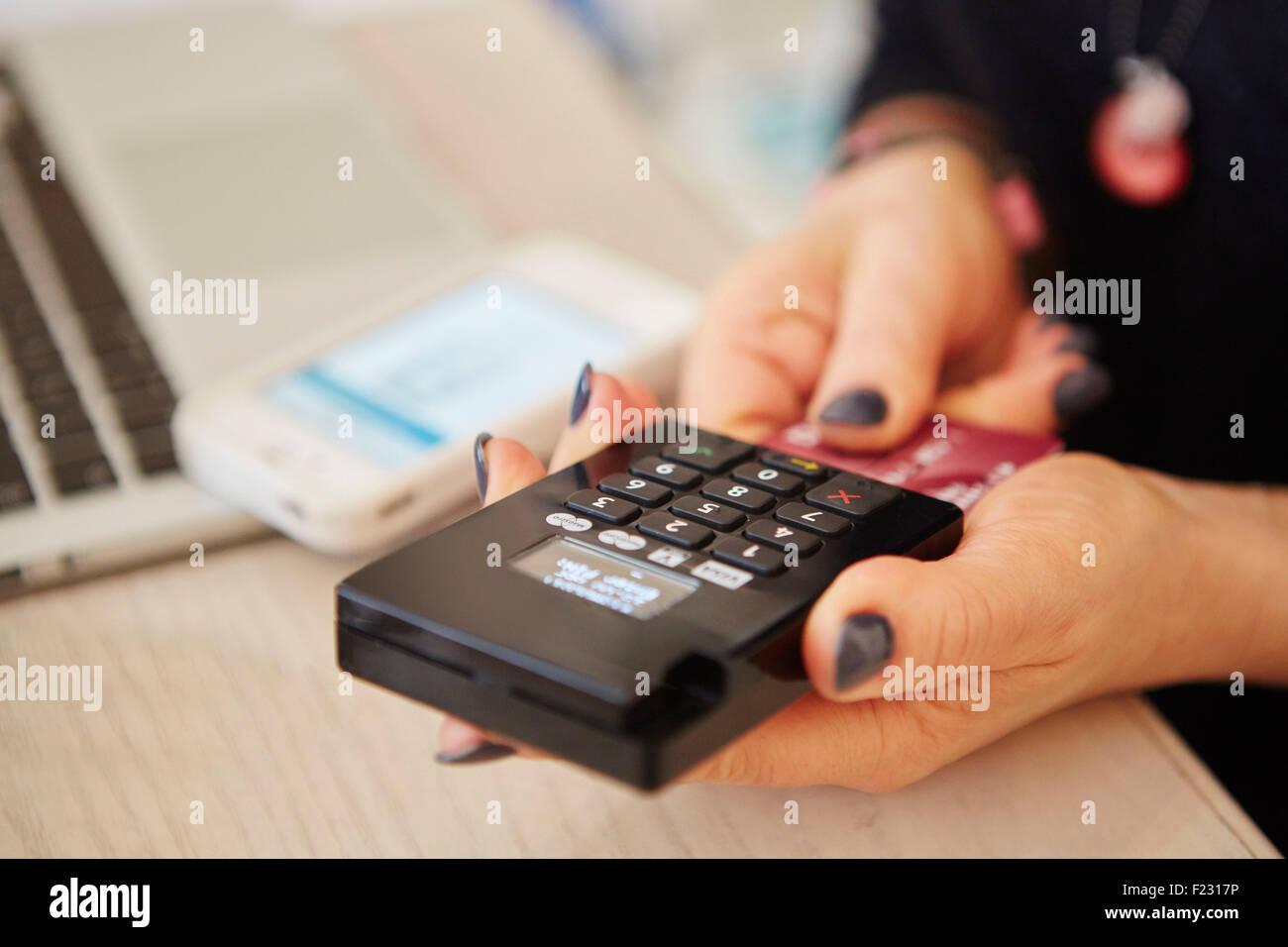 Una donna con le mani in mano in possesso di un lettore di carte di credito, l'elaborazione di pagamento o il pagamento per le merci. Foto Stock