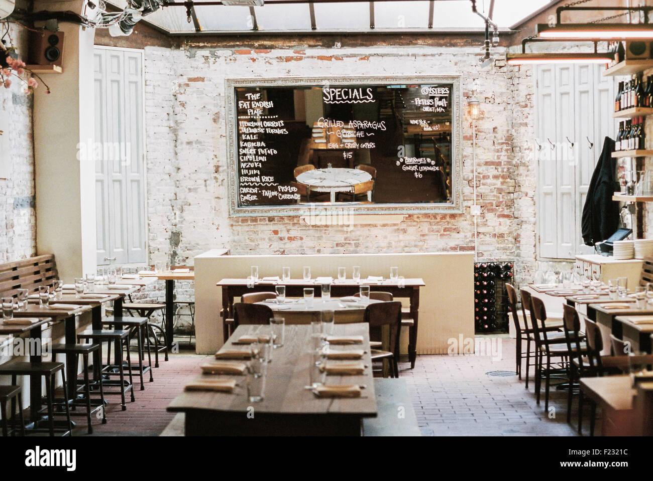 Un ristorante con stretti e lunghi tavoli e sedie a disposizione per un  pasto. Un grande menu Chalk board Foto stock - Alamy