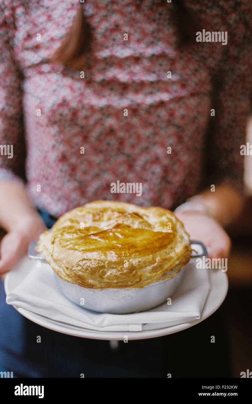 Una donna che porta una fresca pasta cotta al forno e rabboccato la torta su un piatto. Foto Stock