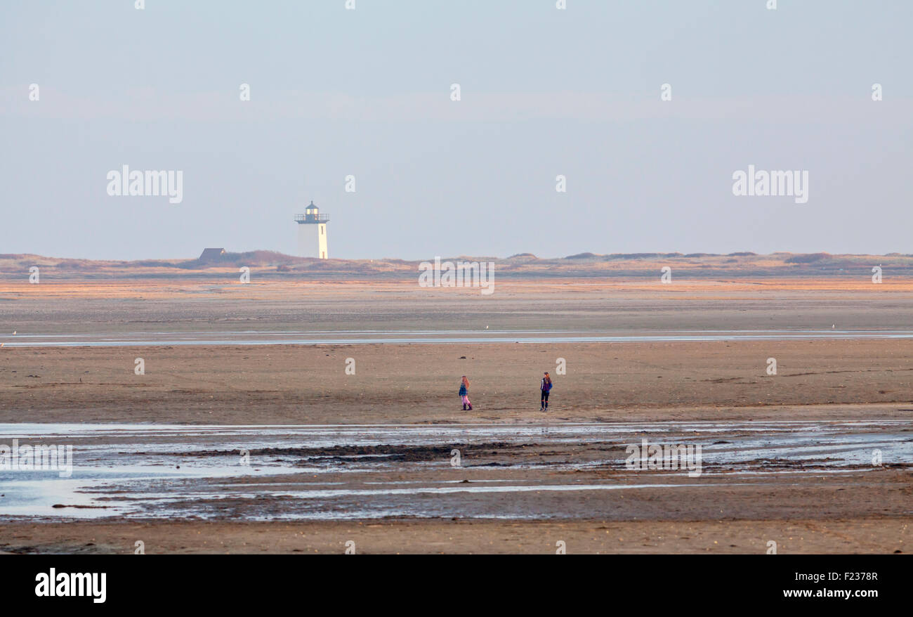 Un faro sulla spiaggia e la gente a piedi Foto Stock