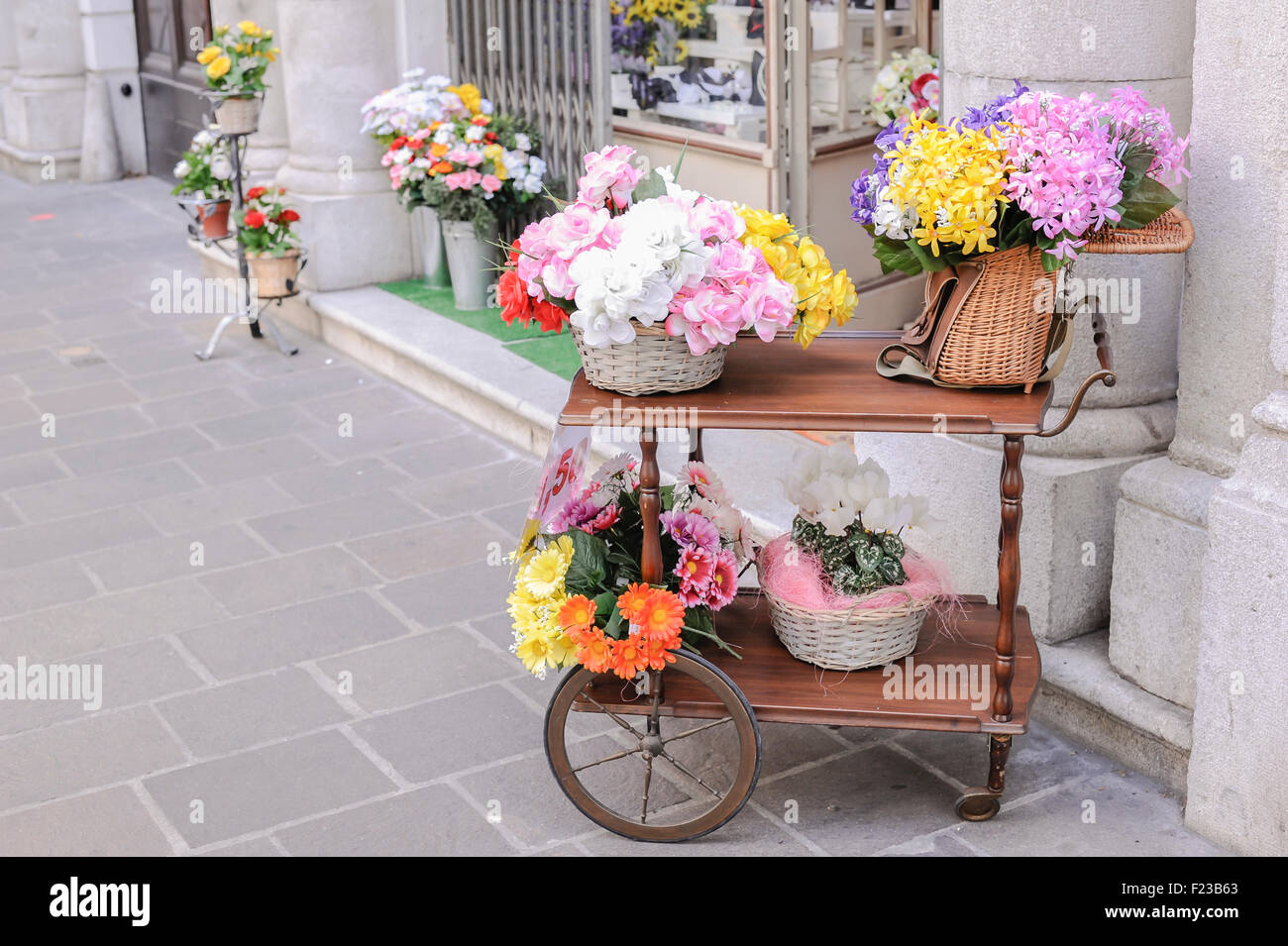 Un carrello con su cesti di vimini e un vecchio pesca in vimini cesto pieno di fiori per la vendita Foto Stock