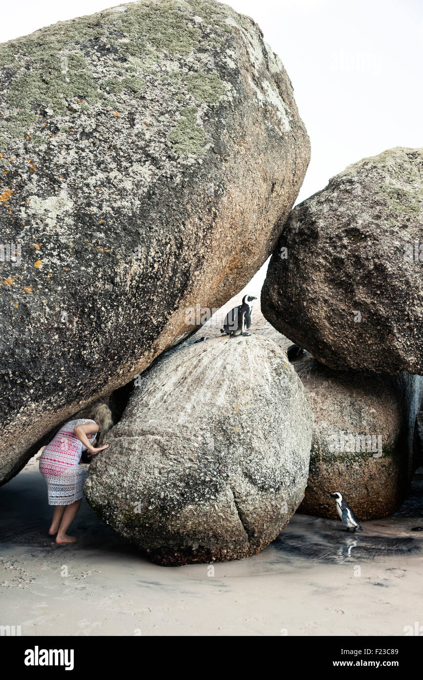 Una donna si accovaccia per schiacciare tra rocce giganti home per i Penguins africani, Boulders Beach National Park, Sud Africa Foto Stock