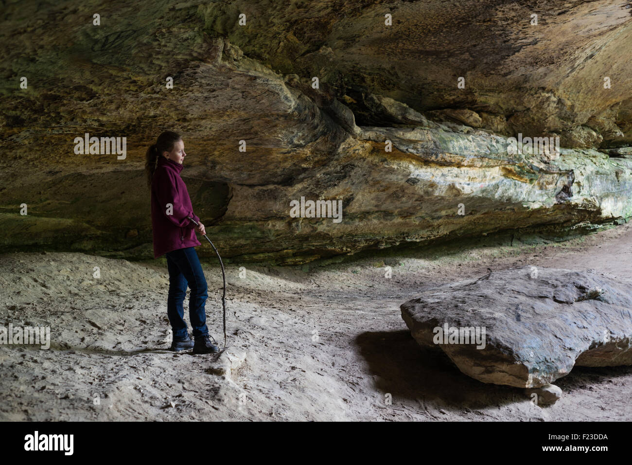 Ragazza con un bastone in piedi sotto una grande roccia sovrasti la cicuta scogliere trail, Hoosier National Forest, inglese, Indiana Foto Stock