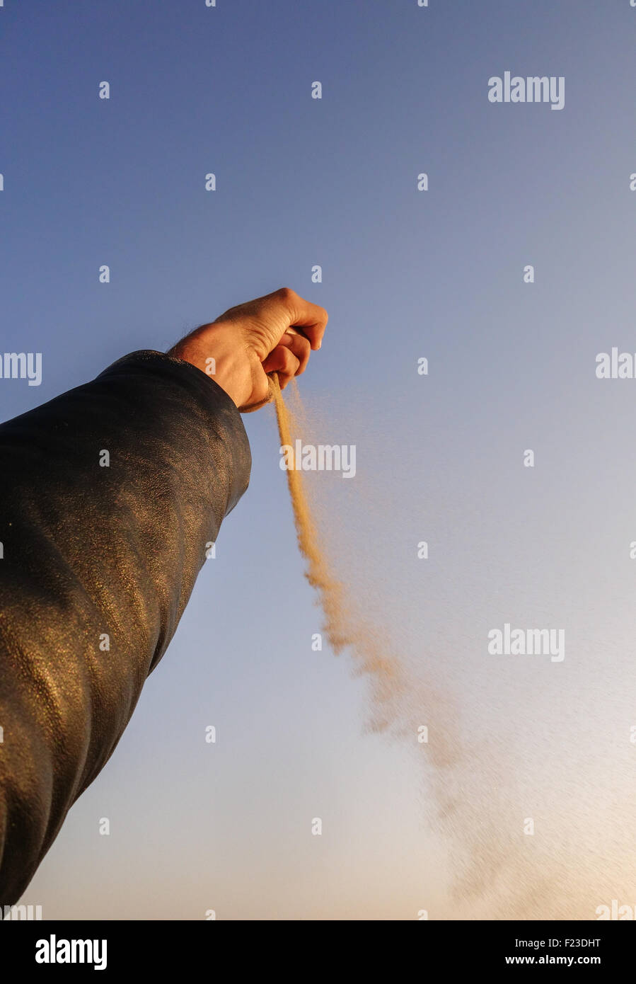 Perde la sabbia dal pugno chiuso soffiati via con il vento oltre il cielo blu. Foto Stock