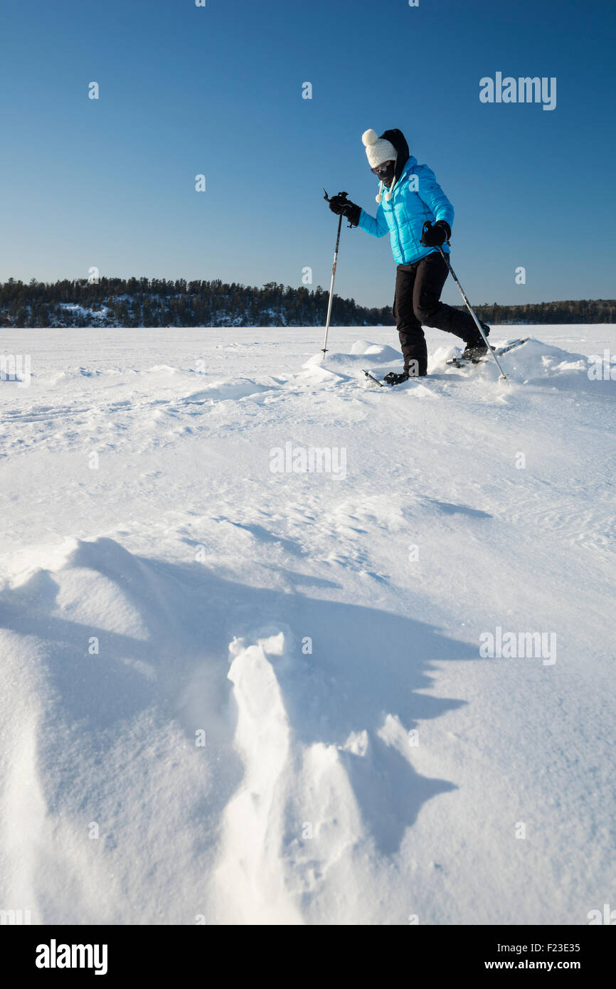 Donna adulta di racchette da neve su un lago ghiacciato a Ely, Minnesota in una fredda temperatura sottozero giornata invernale Foto Stock