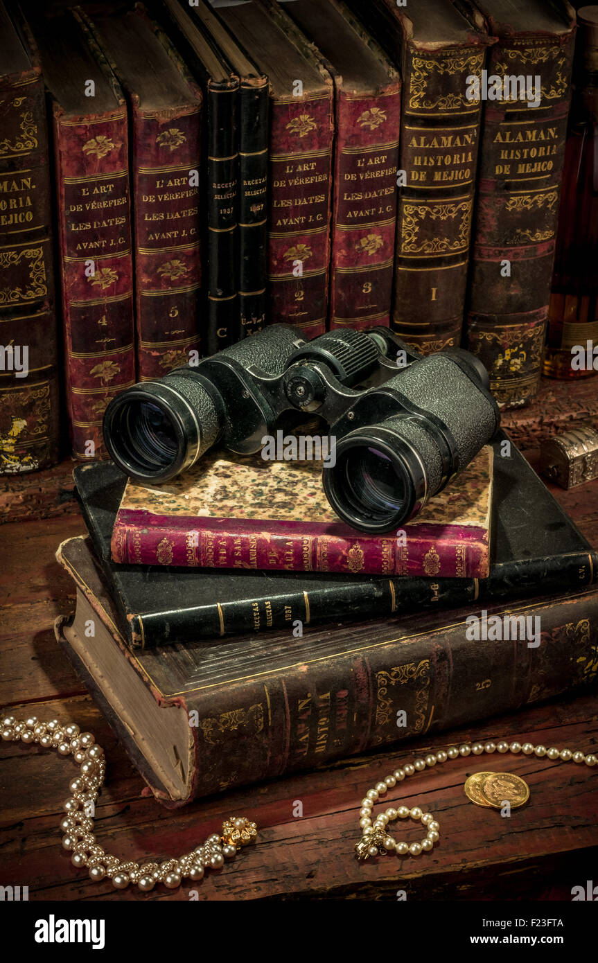 Il binocolo e vecchi libri sulla scrivania in legno Foto Stock