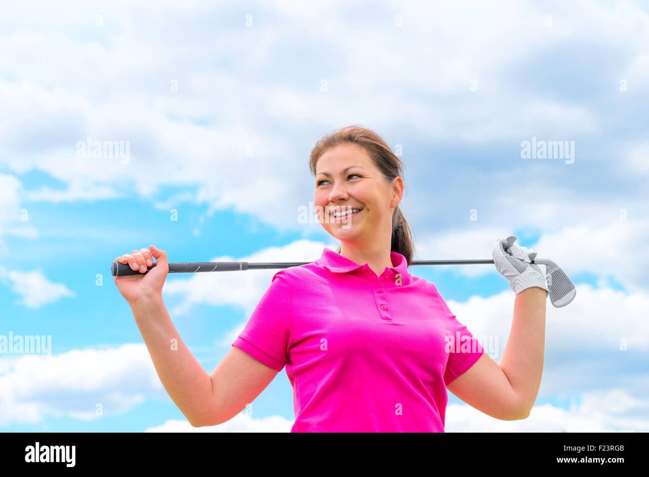 Felice ritratto di una donna golfista con golf club contro il cielo Foto Stock