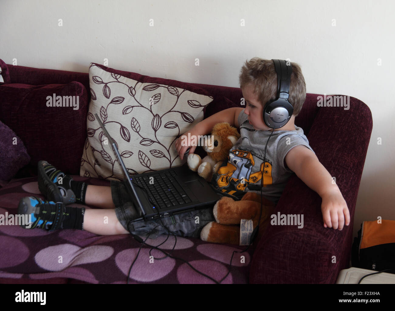 Piccolo boy utilizzando il computer portatile e cuffie Foto Stock