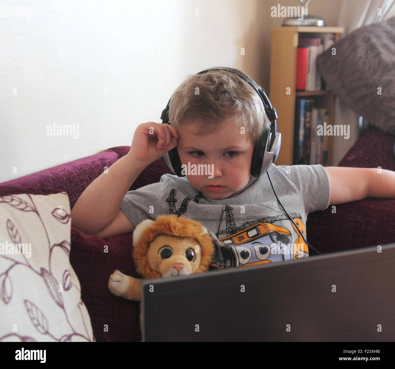 Piccolo boy utilizzando computer portatili con cuffie Foto Stock