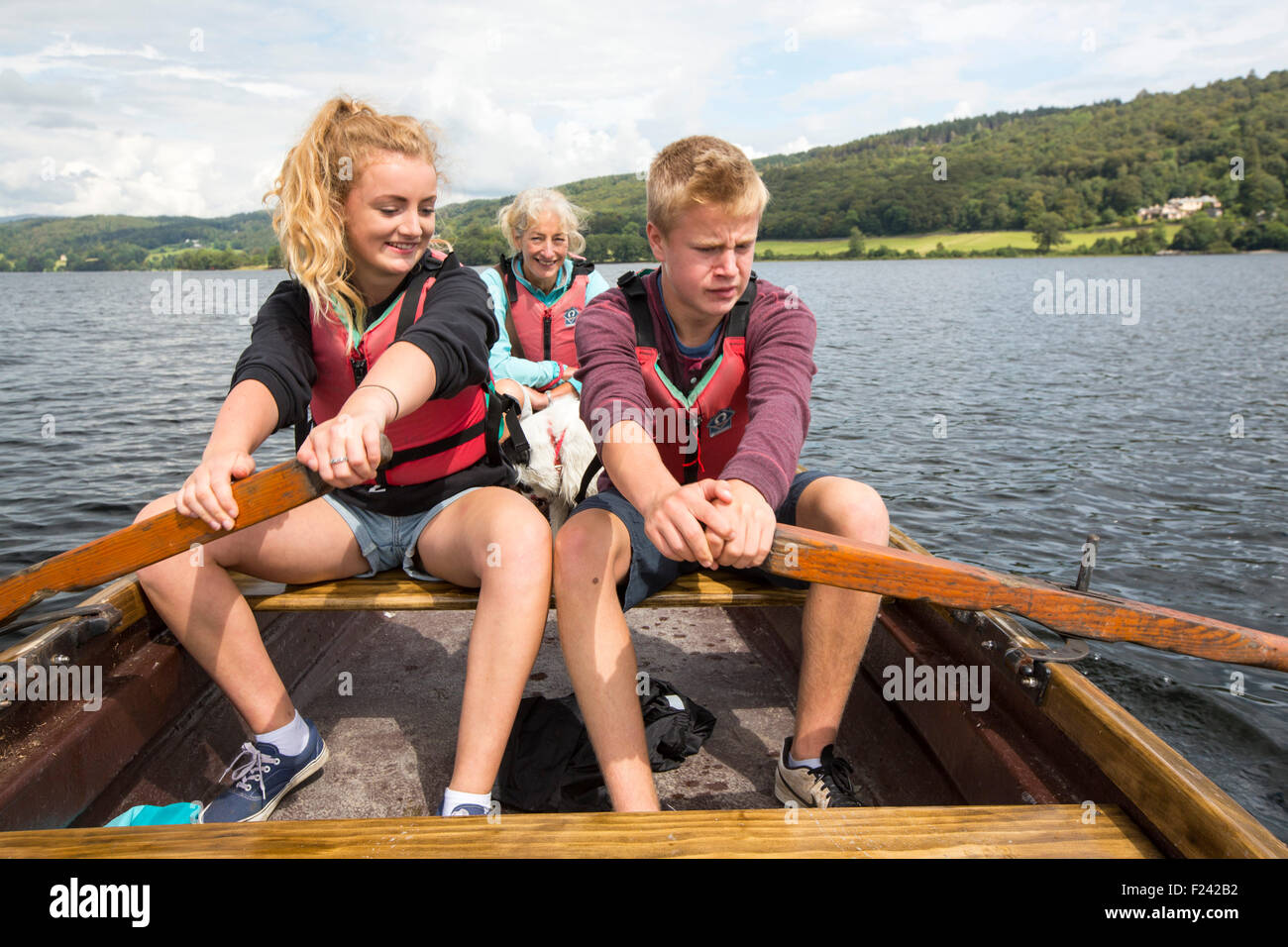 Una donna e due adolescenti in una barca a remi in Coniston Water nel distretto del lago, Cumbria, Regno Unito. Foto Stock