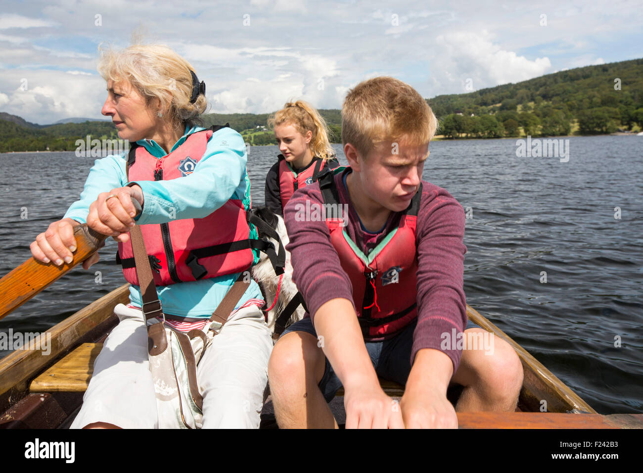 Una donna e due adolescenti in una barca a remi in Coniston Water nel distretto del lago, Cumbria, Regno Unito. Foto Stock