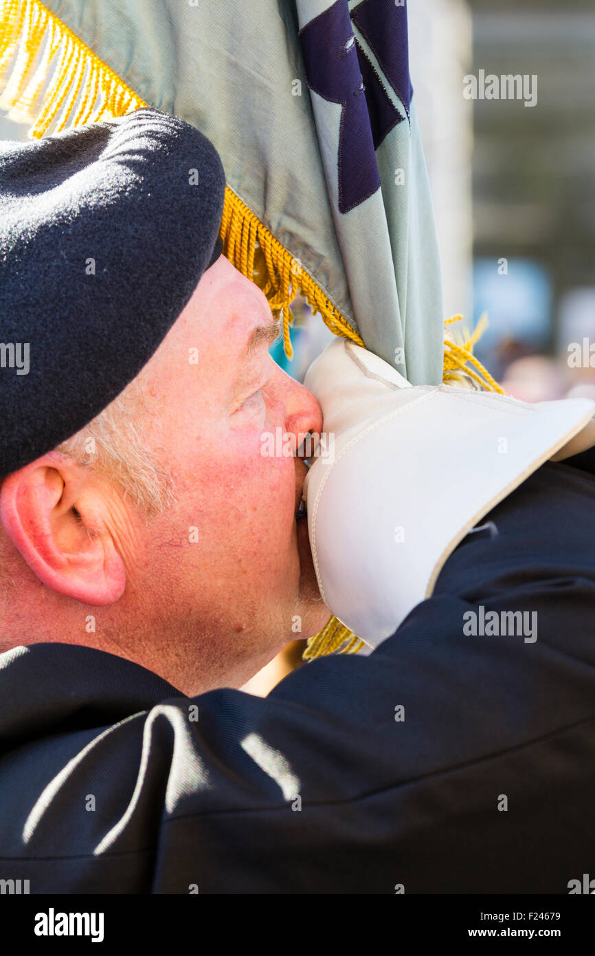 Close up, uomo militare, soldato, permanente per l'attenzione holding standard, bandiera bianca in mano premuto contro il suo naso e bocca durante la cerimonia. Foto Stock